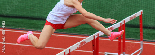 Obraz na płótnie Female Athlete Performs High Jump Over Hurdles During Track Competition on Outdo