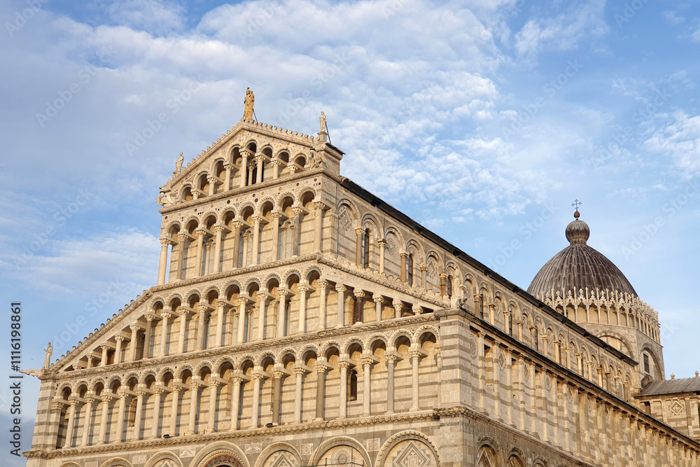Fototapeta premium The intricately designed facade of the Pisa Cathedral, showcasing Romanesque architectural details under a clear blue sky.