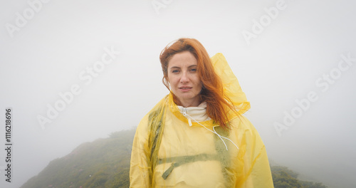 Obraz na plátně Portrait of a woman in a foggy weather looking into the camera hair and coat blowing in the wind