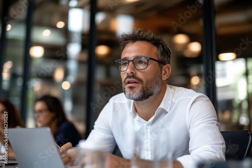 A serious businessman engaged in a corporate meeting, highlighting concentration and professionalism as he interacts with his colleagues in a modern office setting.