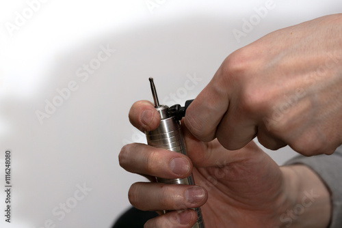 Replacing the nozzle on the burr grinder, men's hands with engraver close-up.  photo