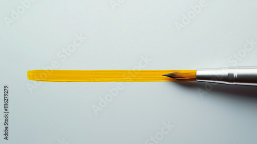 Paintbrush painting a yellow line on white surface 