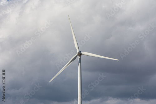 A solitary wind turbine spins gracefully against a dramatic cloudy sky