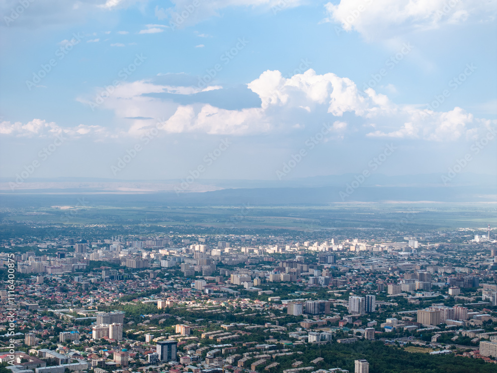 Fototapeta premium Cityscape in summer. Beautiful clouds on the sky. City near the mountains. Top view, drone photo.
