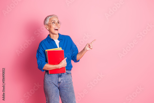 Photo of cheerful impressed lady dressed blue shirt holding copybooks showing empty space isolated pink color background photo