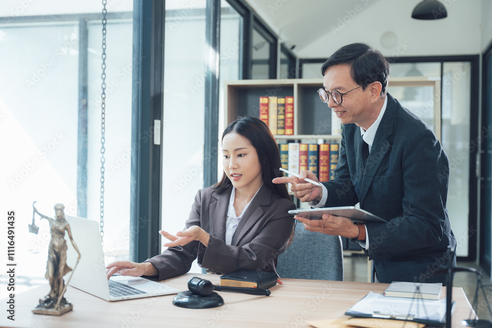 Fototapeta premium Lawyers collaborating on a case: A male and female lawyer are working together in an office, discussing a case on a laptop. They are both wearing professional attire, and the office is well-appointed.