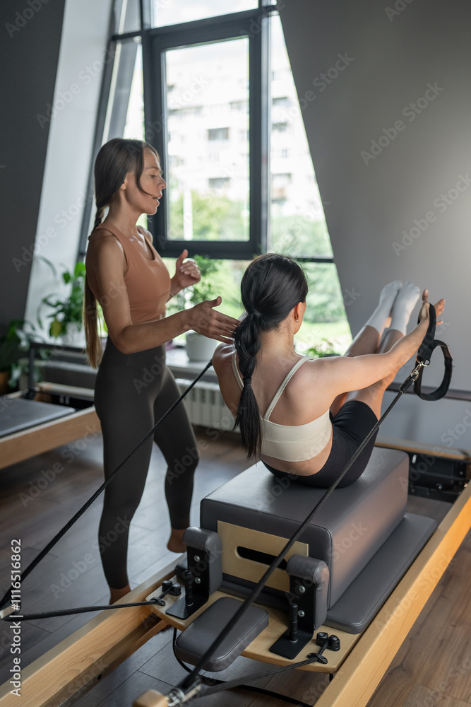 Fototapeta premium Women Doing Pilates in a Modern Studio to Enhance Skills and Improve Health and Wellbeing