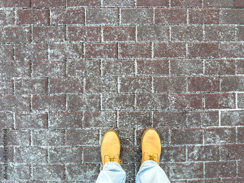 Icy sidewalk with anti-icing reagents improves traction. Winter boots stands on road with de-icing chemicals, reducing accidents by slippery conditions. Technical salt for safety in freezing weather. photo