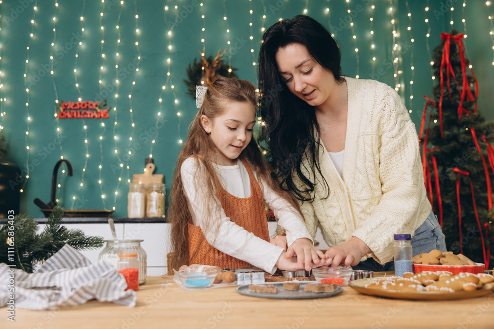 Fototapeta premium Mother and daughter baking christmas cookies together in decorated kitchen