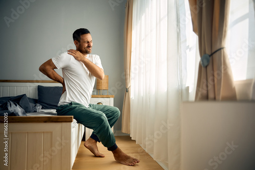 Photography Mid adult man holding his back and shoulder in pain after waking up in morning