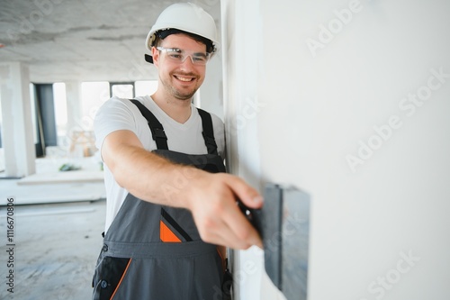 man drywall worker using trowel for plasterer putting stucco on plasterboard white wall photo