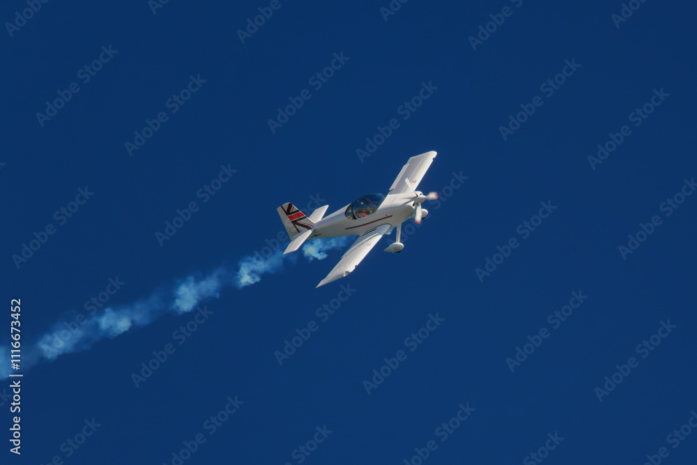 Stunt aerobatic plane performing stunts in blue sky with smoke trail. Concept of speed, difficulty, precision, risk, challenge Stunt aerobatic plane performing stunts in blue sky with smoke trail. Concept of speed, difficulty, precision, risk, challenge