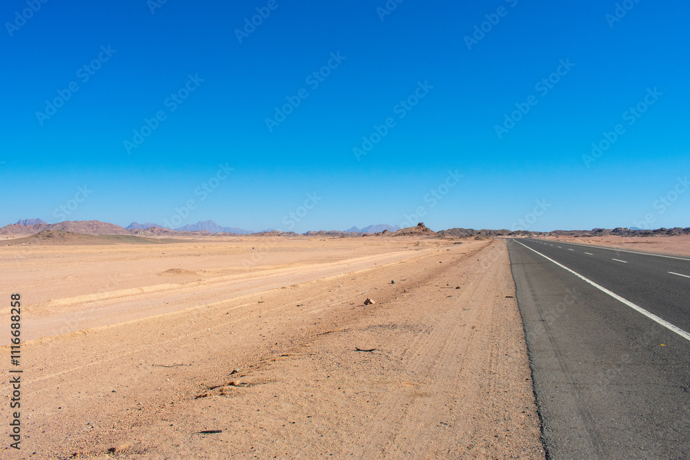 Road in middle of desert near Hurghada Egypt. Empty Asphalt road against blue sky