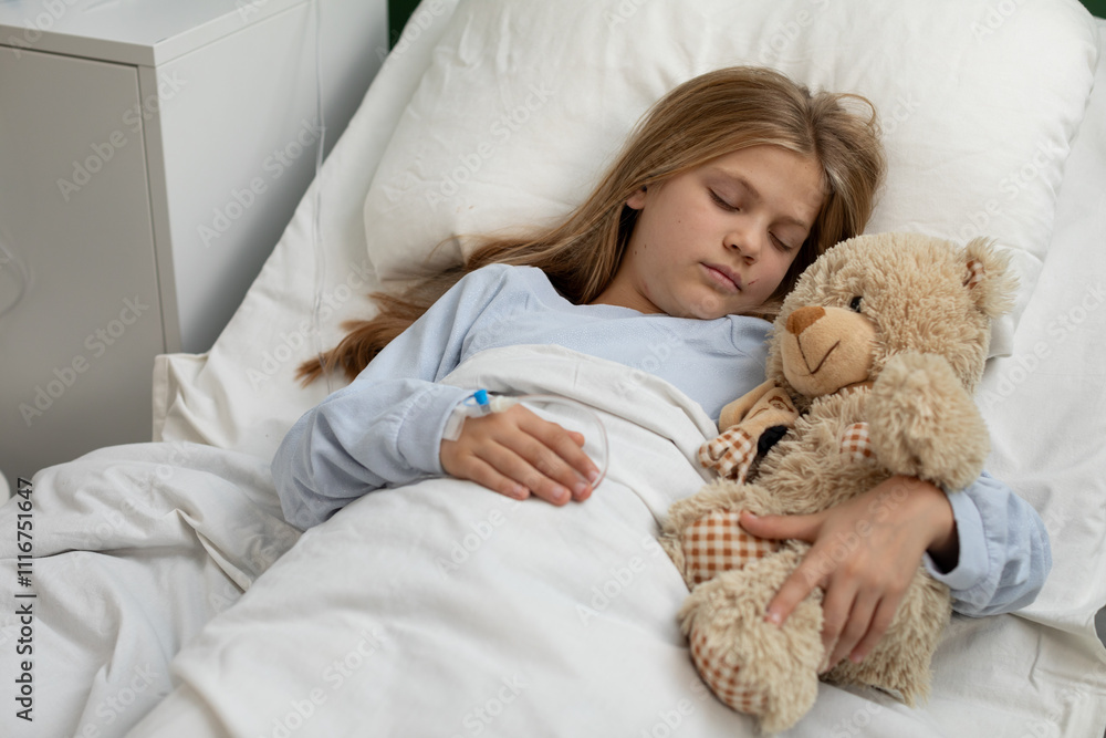 A child is peacefully resting in a hospital bed with a soft teddy bear for comfort and support A child is peacefully resting in a hospital bed with a soft teddy bear for comfort and support