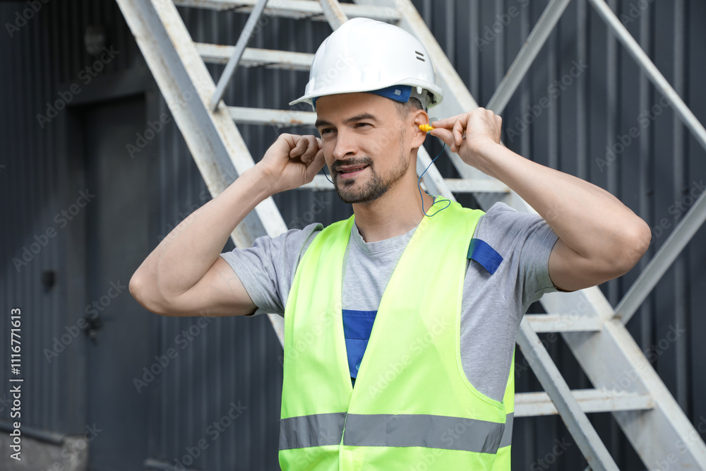 Male builder putting in earplugs outdoors Male builder putting in earplugs outdoors