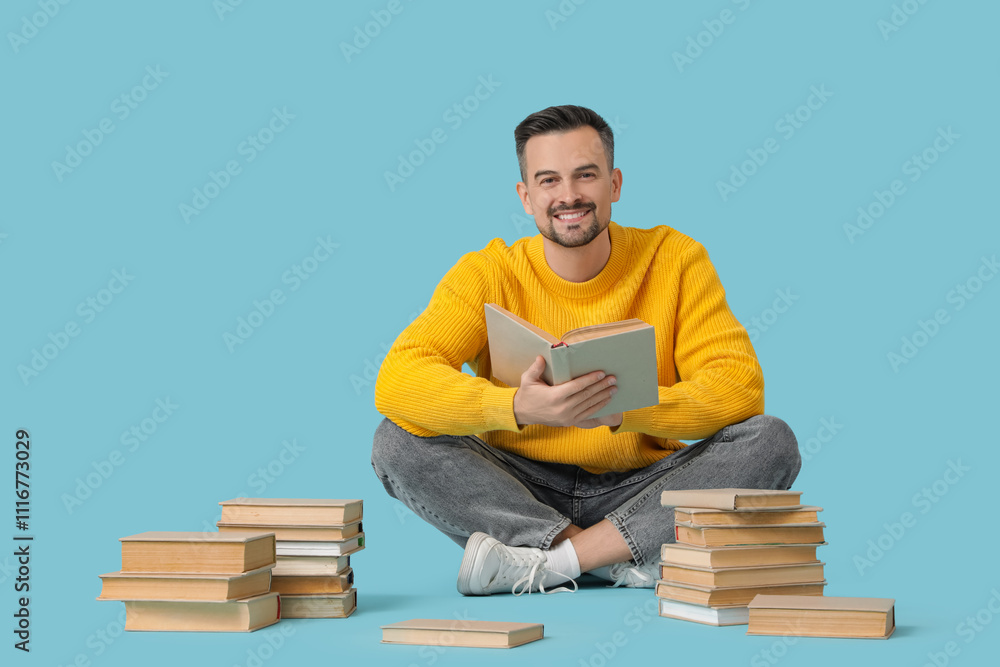Handsome man reading book on blue background Handsome man reading book on blue background