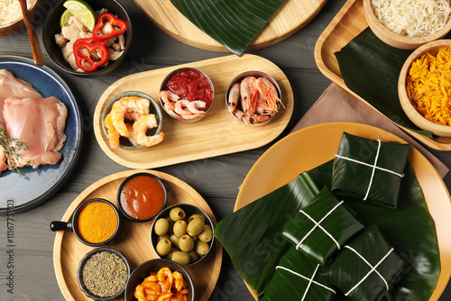 Different food wrapped in banana leaves, products, sauce and spices on wooden table, flat lay photo