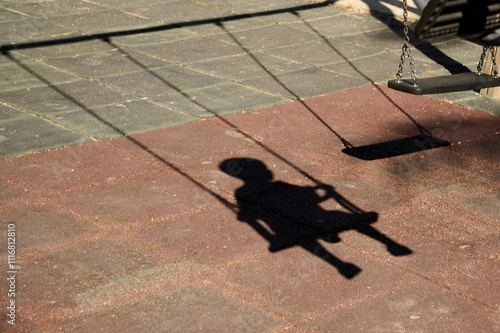 Shadow of a child swinging on a swing at a playground on a sunny day. High quality photo