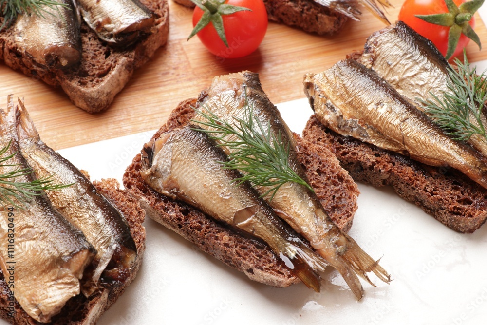 Delicious sandwiches with sprats, dill and tomatoes on table, closeup Delicious sandwiches with sprats, dill and tomatoes on table, closeup