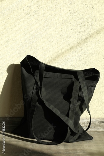 Black eco bag on floor near beige wall. Mockup for design photo