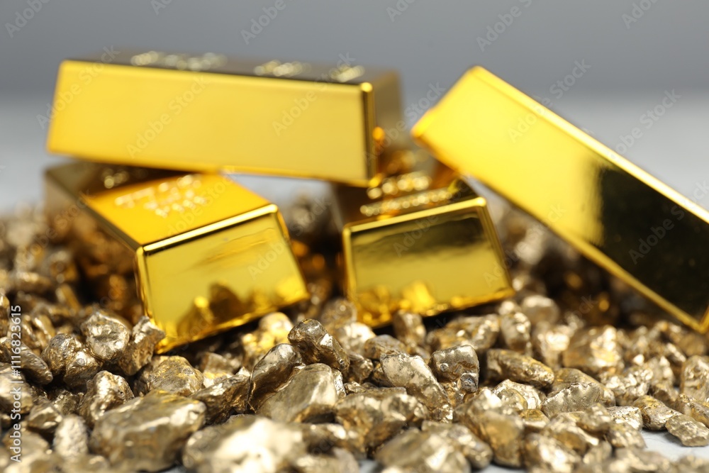 Gold nuggets and bars against blurred background, closeup Gold nuggets and bars against blurred background, closeup