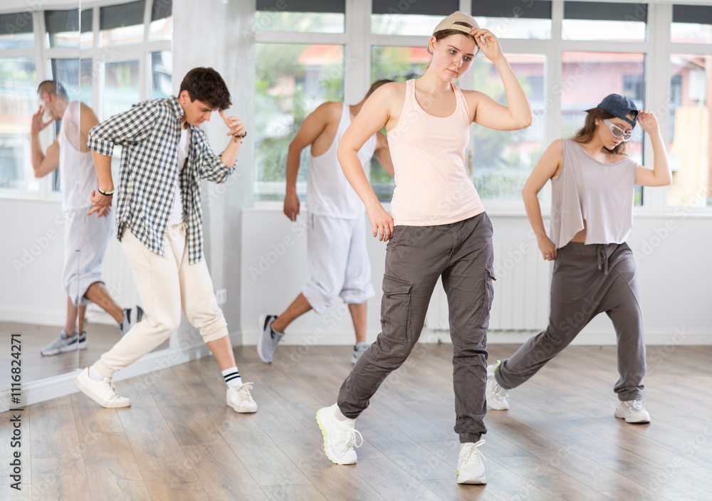 Fototapeta premium Active young group sporty people practicing hip-hop dance in training hall during dancing classes