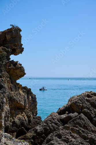 A motorboat sails through the ocean near the rocky island of Anixa, Portugal, 2024. Vertical photo photo