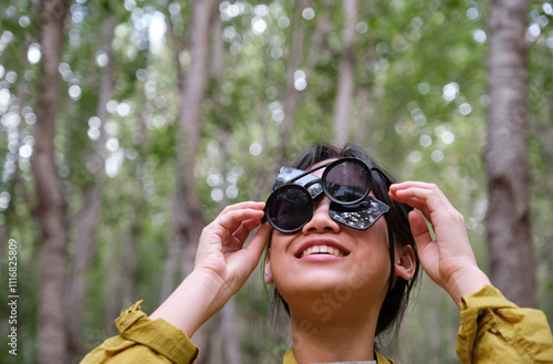 Chinese girl wearing two pairs of sunglasses playing in birch forest photo