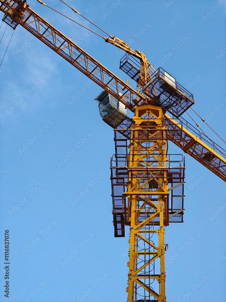 Tower crane under a clear blue sky at a construction site in an urban area Tower crane under a clear blue sky at a construction site in an urban area