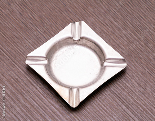 Empty silver square shape ashtray on wooden table