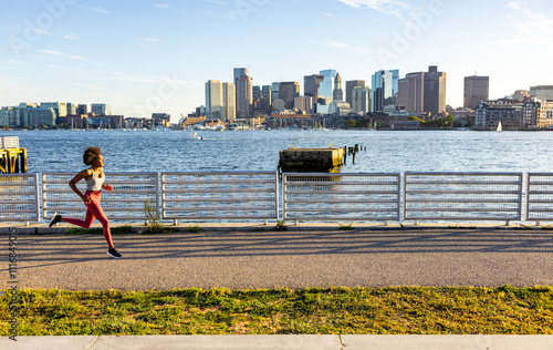 Female black athlete stride running urban waterfront trail photo