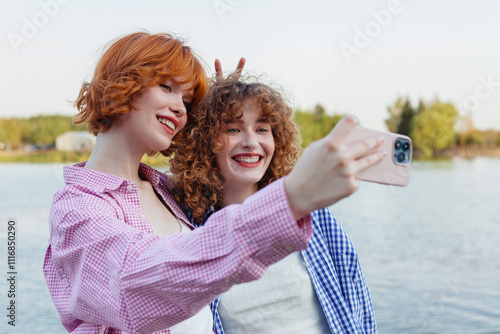 Two friends taking a cheerful selfie by the lake  photo