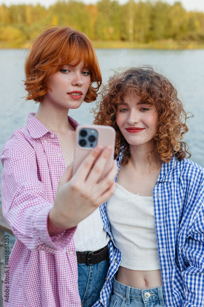 Two friends taking a selfie by the lakeside during a sunny day Two friends taking a selfie by the lakeside during a sunny day