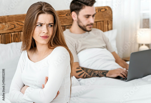 A lot of work concept. Man works on laptop, woman is offended by bed in bedroom. photo