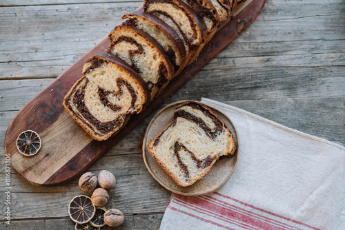 Chocolate swirl bread slices on wooden board with nuts photo