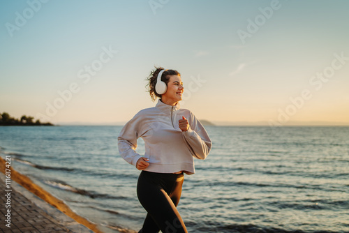 Young caucasian woman running or jogging on the beach at sunset	