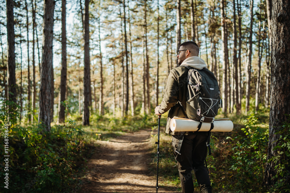 Naklejka premium Young caucasian man hiking or trekking through the forest 