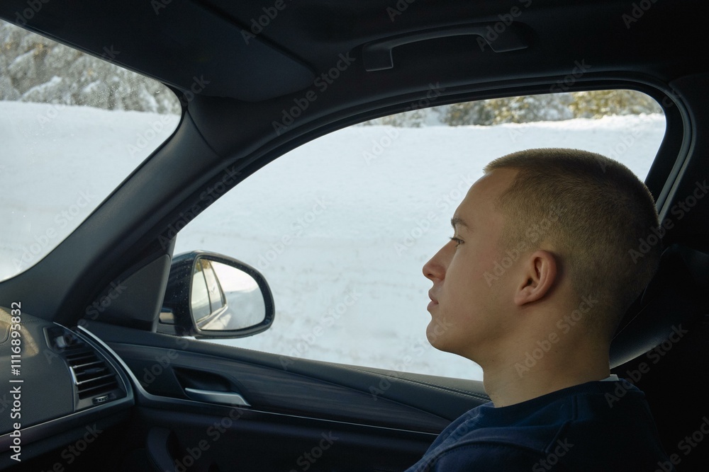 Young man views snowy landscape while driving Young man views snowy landscape while driving