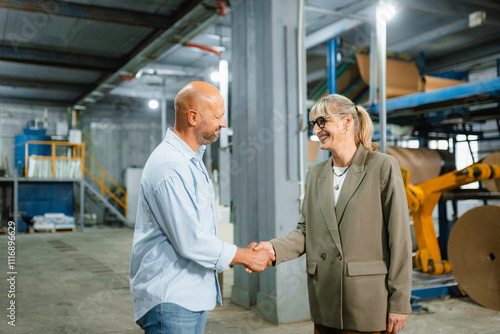 A man and a woman shake hands in a factory photo