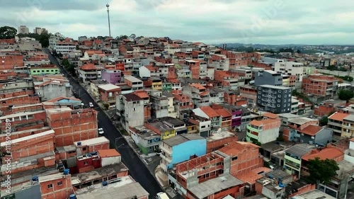 Drone footage of a favela in Osasco, Sao Paulo, Brazil, showcasing colorful and densely packed houses in a bustling urban environment and vibrant culture of Brazilian communities. 