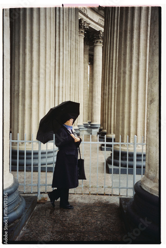 A person stands near colonnade of a grand historical building photo