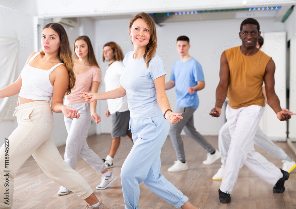Fototapeta premium Group of energetic different people learning dance at dance class