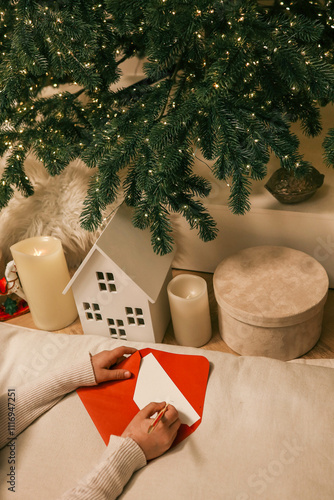 Children preparing Christmas cards with red envelopes near glowing candles and festive decorations. A cozy and creative holiday moment by the Christmas tree photo