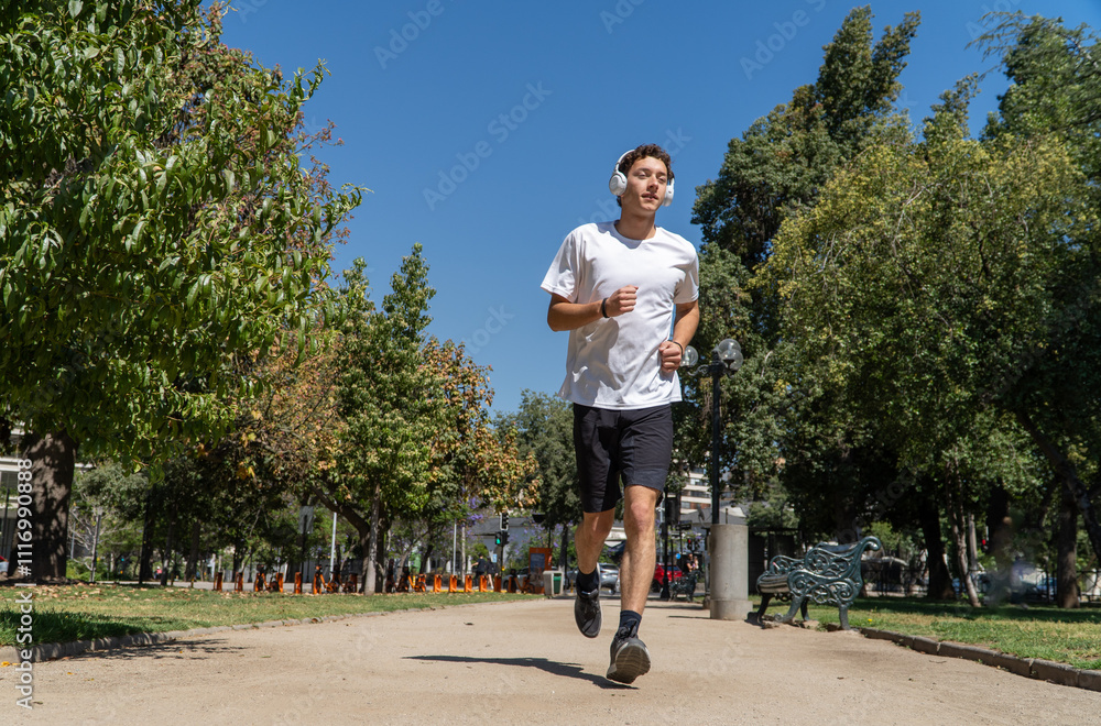 Young Man Jogging in the Park While Listening to Music