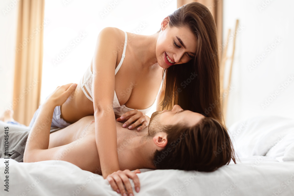 Obraz premium Happy Lovers Enjoying Intimacy Foreplay In Bedroom Indoor. Sexy Husband And Wife Making Love Lying In Bed At Home. Sex Relationship And Passion Concept. Selective Focus