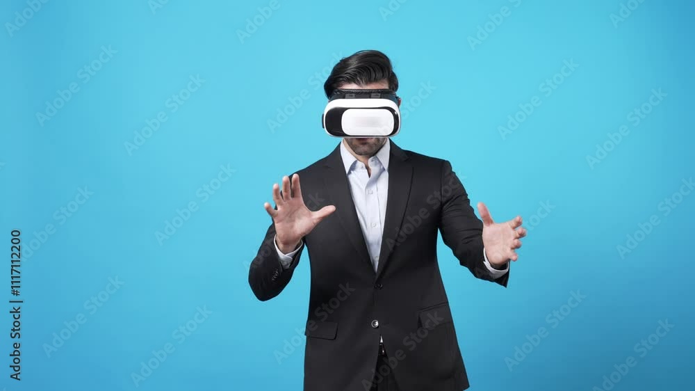 Skilled businessman holding hologram while checking financial data and standing at blue background. Skilled investor looking at statistic chart hologram while planning marketing strategy. Apparatus. Skilled businessman holding hologram while checking financial data and standing at blue background. Skilled investor looking at statistic chart hologram while planning marketing strategy. Apparatus.
