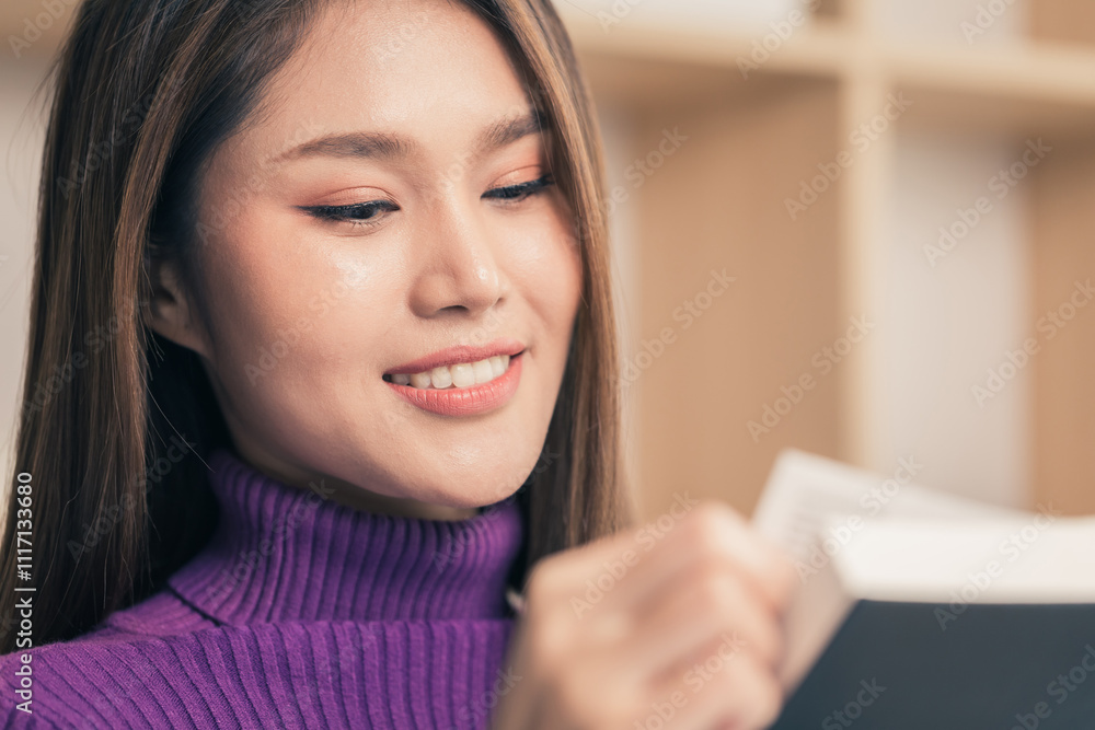 Smiling young smart happy woman in sweater read book novel sit on sofa in living room at home. Close-up Smiling young smart happy woman in sweater read book novel sit on sofa in living room at home. Close-up