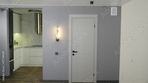 Modern hallway with white walls and a dark gray accent wall is illuminated by a light fixture as it's being turned on. Modern apartment Interior with grey walls. Interior of house home for real estate