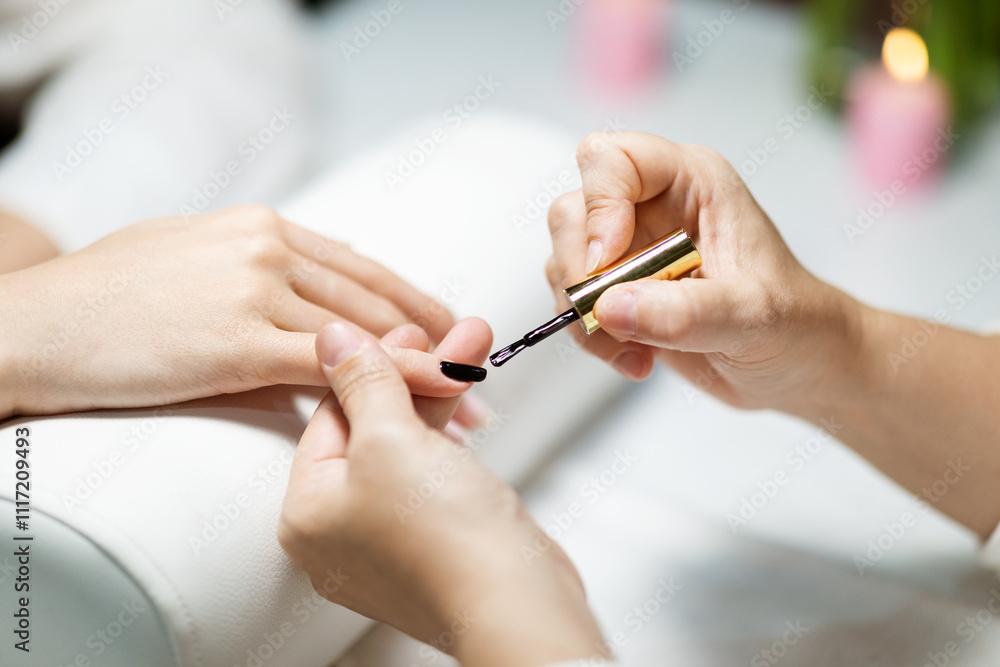 A woman enjoys a pampering session at a fashion-forward salon, where a nail technician carefully applies a nail polish to her hand. The atmosphere is serene and inviting. A woman enjoys a pampering session at a fashion-forward salon, where a nail technician carefully applies a nail polish to her hand. The atmosphere is serene and inviting.