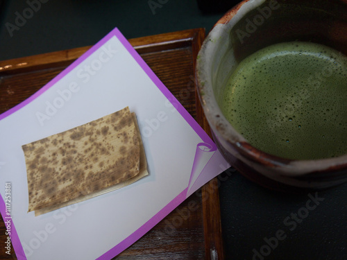 Japanese Matcha-Chawan cup of whipped green tea with dessert covered with dried bamboo leaf photo